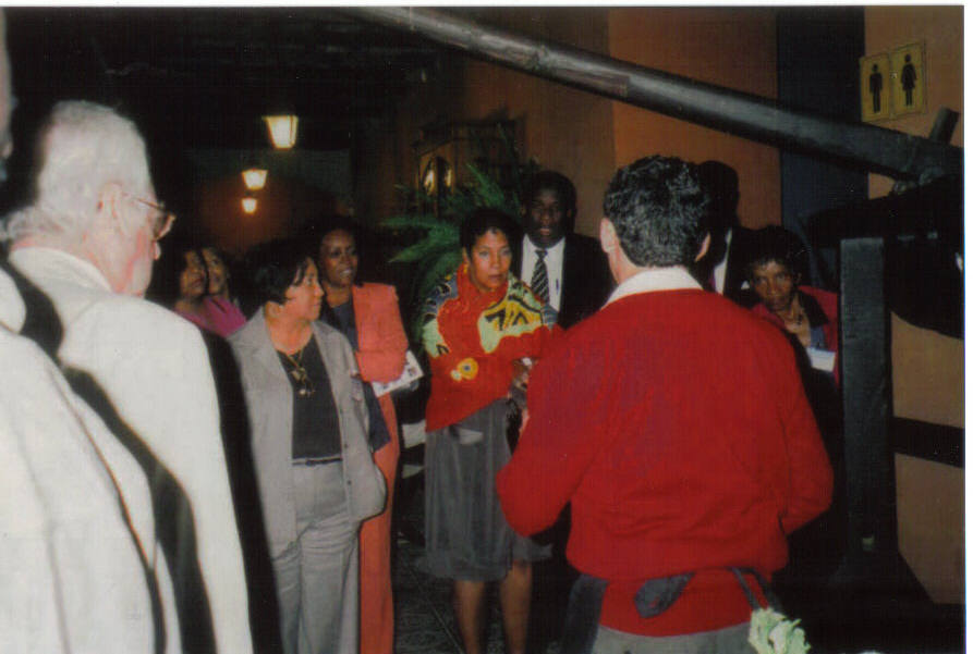 Group of conference attendees stand in prayer and commemoration after viewing the horrors of Hacienda San Jose. Harriett AbuBakr Muhammad looks on as Gisele Arandia speaks.